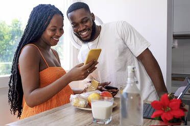 Glückliches Paar teilt sich ein Smartphone zu Hause - GGGF01203