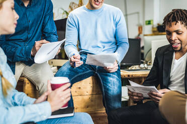 Konzentrierte Gruppe von Arbeitnehmern in förmlicher Kleidung, die mit Dokumenten arbeiten und sich in einem Büro versammeln - ADSF36506