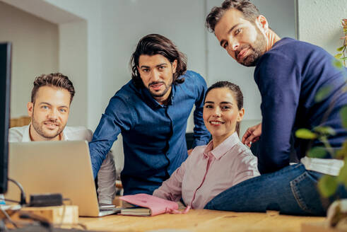 Konzentrierte Männer und Frauen in formeller Kleidung beim Surfen am Computer, während sie gemeinsam an einem Geschäftsprojekt in einem hellen, modernen Büro arbeiten - ADSF36526