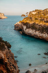 Atemberaubende Kulisse der massiven Felsenklippe über dem wellenförmigen, endlos blauen Meer an einem sonnigen Tag auf den Balearischen Inseln - ADSF36650