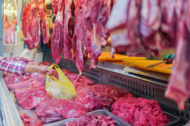 Unbekannter Kunde nimmt den Sack Fleisch beim Besuch einer Metzgerei auf dem Markt - ADSF36668
