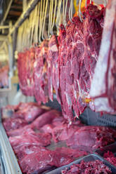 Weichzeichner von Bündel von rohem Fleisch hängen auf Schiene über Metall Stand der Metzgerei auf dem Markt - ADSF36671