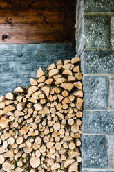Pile of chopped firewood stacked near stone wall in house in daytime in countryside - ADSF36710