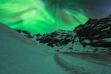 Landschaft der felsigen Klippen mit schneebedeckten Gipfeln unter hellen Aurora Borealis Lichter in Agvatnet See - ADSF36820
