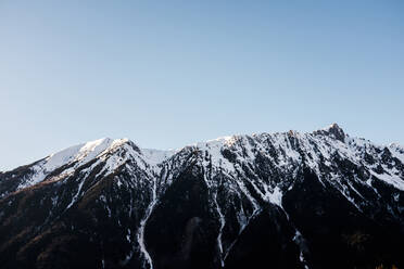 Peals von rauen Bergkette mit Schnee bedeckt in Hochland gegen blauen Himmel auf kalten Wintertag in der Natur gelegen - ADSF36837
