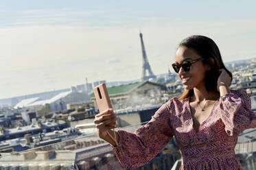 Junge Frau nimmt Selfie durch Smartphone mit Eiffelturm im Hintergrund, Paris, Frankreich - KIJF04494