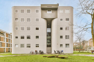 Kreative Gestaltung moderner mehrstöckiger Hausfassaden in der Nähe von grünem Gras unter blauem Himmel in den Niederlanden - ADSF36885