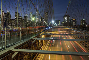 Der Verkehr überquert die Brooklyn Bridge mit der Skyline von Manhattan dahinter bei Nacht, Manhattan, New York, Vereinigte Staaten von Amerika, Nordamerika - RHPLF22946