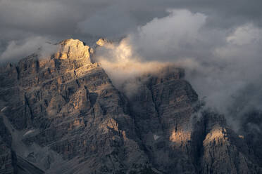 Sunset light illuminating some Dolomites rocks wrapped in clouds and fog, Dolomites, Italy, Europe - RHPLF23093