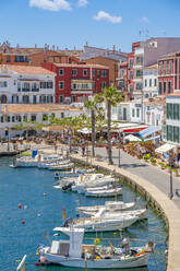 Blick auf bunte Cafés, Restaurants und Boote im Hafen vor blauem Himmel, Cales Fonts, Menorca, Balearen, Spanien, Mittelmeer, Europa - RHPLF23105