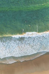 Aerial view of Bedruthan Carnewas Steps beach with surfers riding waves at sunset, Cornwall, United Kingdom. - AAEF15513