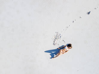 Aerial view of woman in white swimsuit on white beach, Cape Town, South Africa. - AAEF15516