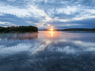 Luftaufnahme des Sonnenuntergangs über einem ruhigen See während der Mitternachtssonne in Overtornea, Schweden. - AAEF15531