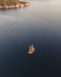 Luftaufnahme eines Piratenschiffs, das bei Sonnenuntergang an der Küste von Capo D'Enfola, Insel Elba, Toskana, Italien, entlangfährt. - AAEF15709