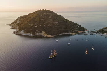 Luftaufnahme eines Piratenschiffs, das bei Sonnenuntergang an der Küste von Capo D'Enfola, Insel Elba, Toskana, Italien, entlangfährt. - AAEF15710