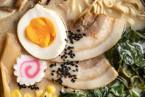 Nahaufnahme von appetitlichen japanischen Ramen mit gekochtem Ei und Pilzen in einer Schüssel serviert - ADSF36963