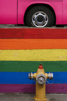 Traditionelle Hydrant auf der Straße in der Nähe Wand mit gemalten LGBT Regenbogen Hintergrund am Straßenrand mit geparkten rosa Bus - ADSF37347