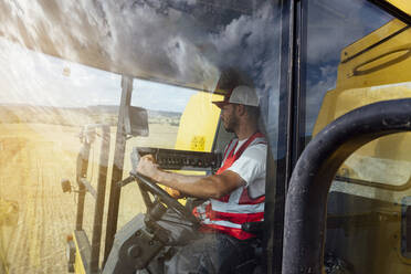 Durch das Fenster Seitenansicht des Mähdreschers in einheitlichen Ernte Getreidepflanzen in landwirtschaftlichen Bereich bei der Arbeit im ländlichen Raum - ADSF37358
