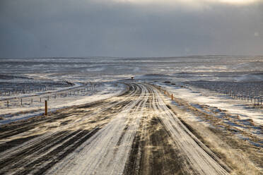 Leere, schneebedeckte Straße in einem Hochlandtal im Winter in Island - ADSF37388