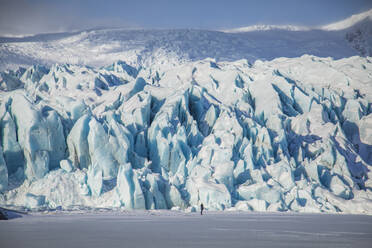 Unrecognizable traveler hiker admiring spectacular scenery of frozen seashore with ice and snow in winter in Iceland - ADSF37415