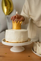 Unbekannte Frau zündet auf einer Geburtstagsparty eine Kerze an einem Cupcake an - ADSF37471