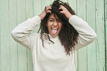 Young woman with hands in hair sticking out tongue - KIJF04498