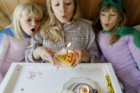 Mother with children blowing candle on cake at home - TYF00412