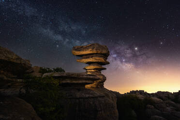 Green tree and unusual stone formation located against night sky with bright stars in countryside - ADSF37482