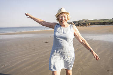 Happy woman with arms raised enjoying vacation at beach - UUF27203