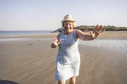 Cheerful senior woman dancing and having fun on beach at vacation - UUF27205