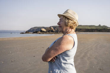 Senior woman with arms crossed standing at beach - UUF27207