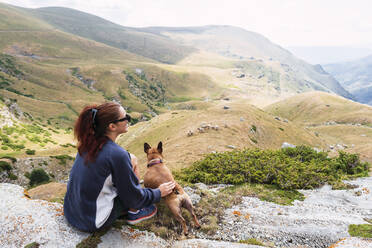 Frau mit Hund vor einem Berg sitzend - PNAF04513