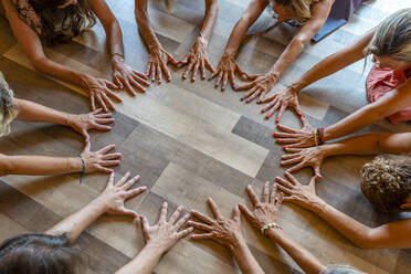 Gruppe von Freunden beim Meditieren mit den Händen auf dem Boden - DLTSF03072