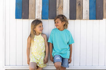 Smiling cute girl with boy leaning on wooden wall - MEGF00015