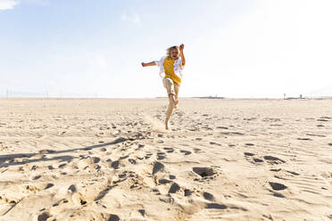 Junge springt und spielt am Strand an einem sonnigen Tag - MEGF00057