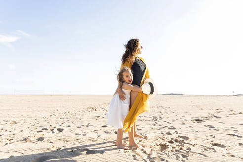 Mature woman with daughter standing at beach on sunny day - MEGF00061