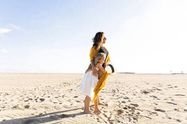 Mädchen umarmt Mutter am Strand an einem sonnigen Tag - MEGF00062