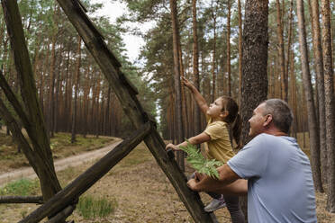 Mädchen klettert auf Leiter und gestikuliert zu Mann im Wald - TOF00099