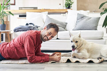 Glücklicher Mann, der eine Kaffeetasse trinkt und vor einem Hund sitzt - VEGF05915