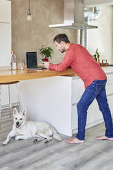 Man using smart phone leaning on table at home - VEGF05925