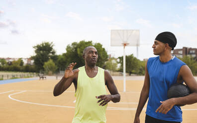 Älterer Mann im Gespräch mit seinem Sohn auf dem Basketballplatz - JCCMF07167