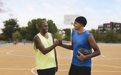 Lächelnder Vater und Sohn beim Händeschütteln auf dem Sportplatz - JCCMF07168