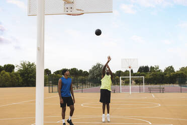 Young man looking at father shooting basketball in hoop - JCCMF07170