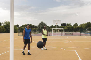 Vater und Sohn betrachten einen fallenden Basketball auf dem Sportplatz - JCCMF07171