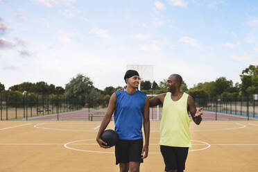 Father talking with son walking at basketball court - JCCMF07177