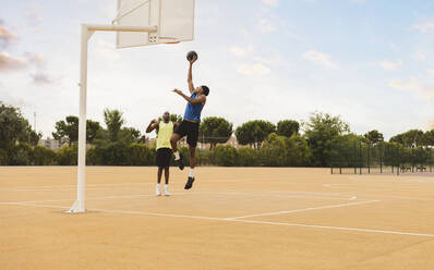 Vater sieht seinen Sohn an, der den Basketball in den Korb wirft - JCCMF07179