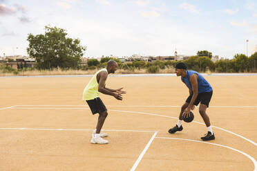 Son dribbling basketball playing with father at sports court - JCCMF07182