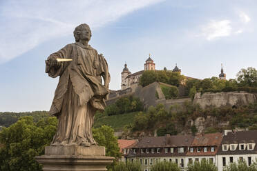 Deutschland, Bayern, Würzburg, Statue des Heiligen Kolonatus mit Festung Marienberg im Hintergrund - FCF02109