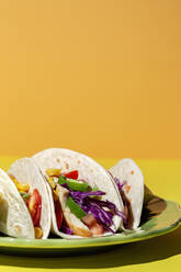 Homemade Mexican Tacos with fresh vegetables and chicken with strong light on yellow background. Healthy food. Typical Mexican - ADSF37531
