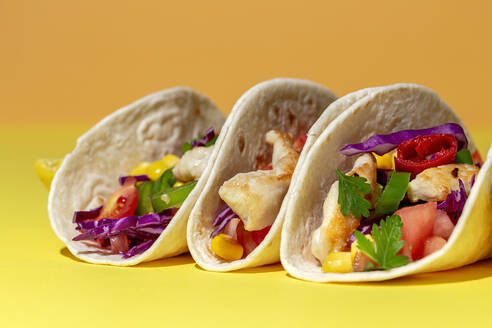 Hausgemachte mexikanische Tacos mit frischem Gemüse und Huhn mit starkem Licht auf gelbem Hintergrund. Gesundes Essen. Typisch mexikanisch - ADSF37534